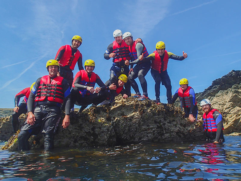 Large Coasteering stag do party taking a group photo upon a rocky outcrop