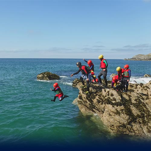 Little child take his first Coasteering jump into the sea